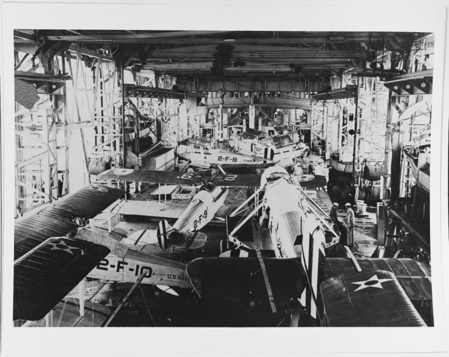 Aircraft in the ship’s hangar, during the 1920s. The larger plane in the foreground is a Douglas DT torpedo bomber, with its wings removed. Other aircraft are Vought VE-7s of Fighting Squadron Two (VF-2).(NHHC)
