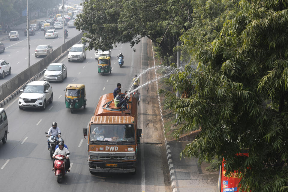 Civic workers sprinkle water to clear the dust on tress as the city is enveloped under thick smog in New Delhi, India, Tuesday, Nov. 12, 2019. A thick haze of polluted air is hanging over India's capital, with authorities trying to tackle the problem by sprinkling water to settle dust and banning some construction. The air quality index exceeded 400, about eight times the recommended maximum. (AP Photo/Manish Swarup)