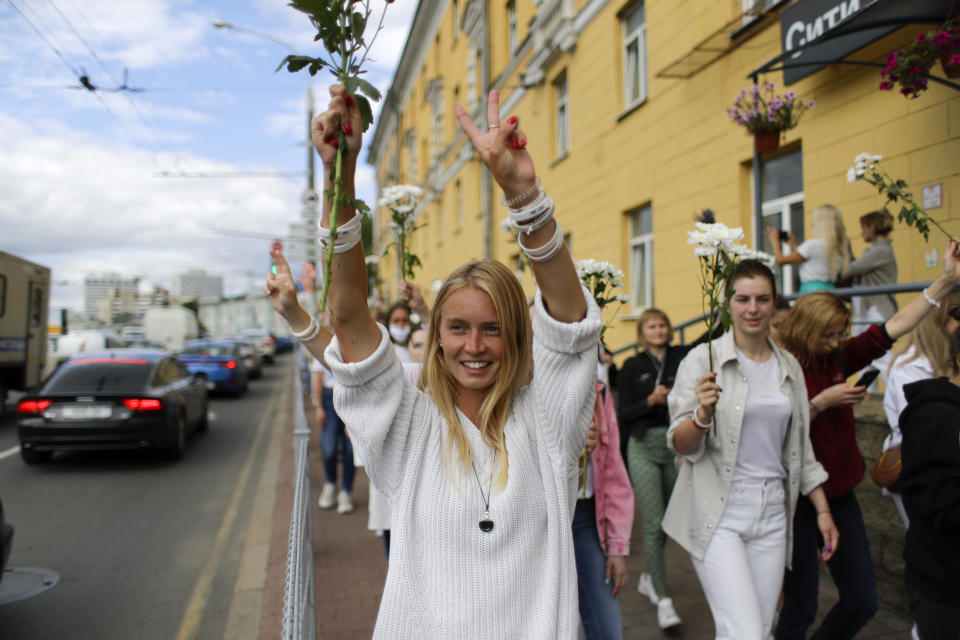 A Belarusian woman shows a victory sign during a rally in solidarity with protesters injured in the latest rallies against the results of the country's presidential election in Minsk, Belarus, Thursday, Aug. 13, 2020. Hundreds of people were back on the streets of Belarus' capital on Thursday morning, forming long "lines of solidarity" in protest against an election they say was rigged to extend the rule of the country's authoritarian leader and against a crackdown on rallies that followed the vote. (AP Photo/Sergei Grits)