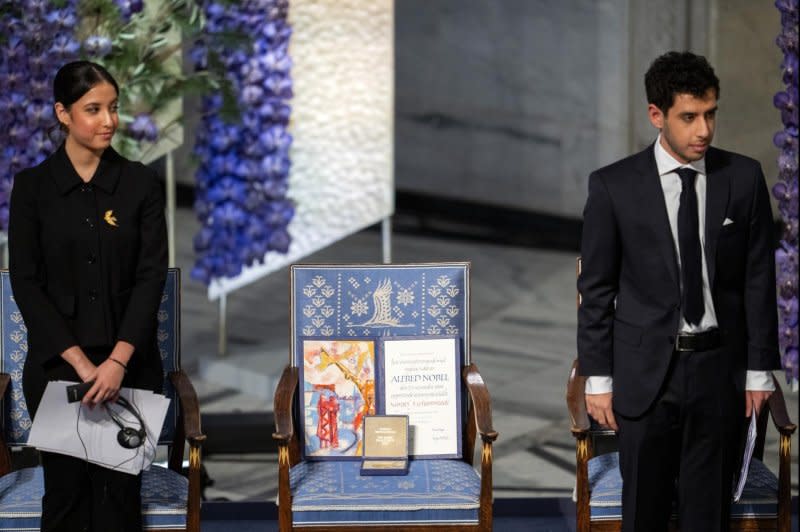 Kiana (L) and Ali Rahmani (R) stand next to an empty chair with the peace prize diploma for their mother, Iranian human rights activist and Nobel Peace Prize 2023 winner Narges Mohammadi, during the awarding of the Nobel Peace Prize for 2023 in Oslo, Norway, on Sunday. Photo by Fredrik Varfjell/EPA-EFE