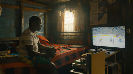 Kenya Ice Lions assistant captain Joseph Thuo watches an NHL hockey game on television at his home in Nairobi, Kenya, in this still image handout photo taken from video August 2018 and provided October 16, 2018. Tim Horton's/Handout via REUTERS