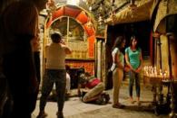 Palestinian swimmer Mary Al-Atrash (R), 22, who will represent Palestine at the 2016 Rio Olympics, looks at candles as she prays at The Church of the Nativity in the West Bank town of Bethlehem June 27, 2016. REUTERS/Ammar Awad