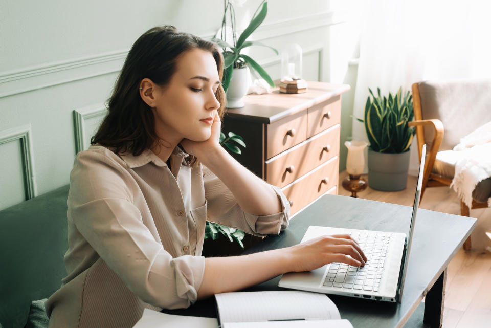 a woman looking somberly at her laptop