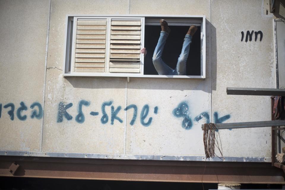 A settler jumps into a trailer in Amona outpost in the West Bank, Wednesday, Feb. 1, 2017. Israeli forces have begun evacuating a controversial settlement Amona, which is the largest of about 100 unauthorized outposts erected in the West Bank without permission but generally tolerated by the Israeli government. The writing reads: "Eretz Israel we did not betray ". (AP Photo/Ariel Schalit)