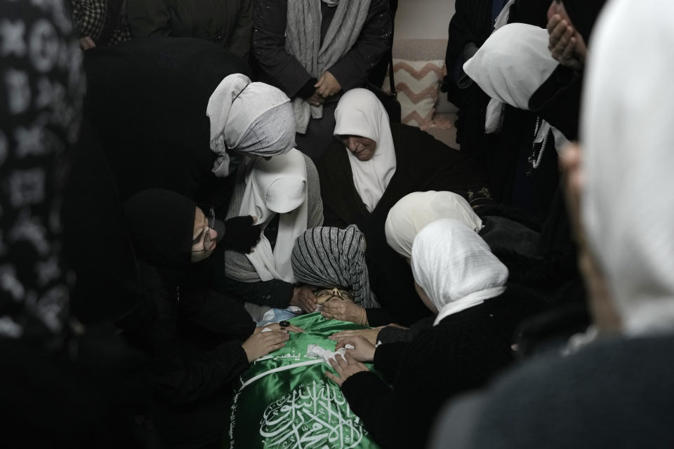 Palestinian women gather around the body of Muhammad Jalamneh, draped in the Hamas militant group flag, in the morgue of Ibn Sina Hospital after he was killed in an Israeli military raid in the West Bank town of Jenin, Tuesday, Jan. 30, 2024. Armed Israeli undercover forces disguised as women and medical workers stormed the hospital on Tuesday, killing a few Palestinian militants. The Palestinian Health Ministry condemned the incursion on a hospital, where the military said the militants were hiding out.(AP Photo/Majdi Mohammed)