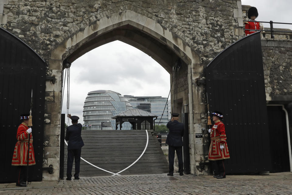Yeoman Warders, left and and fourth left, standby as a drawbridge is lowered during a ceremony to mark the reopening of the Tower of London for visitors, in London, as the British government continues to relax its coronavirus restrictions, Friday, July 10, 2020. (AP Photo/Matt Dunham)