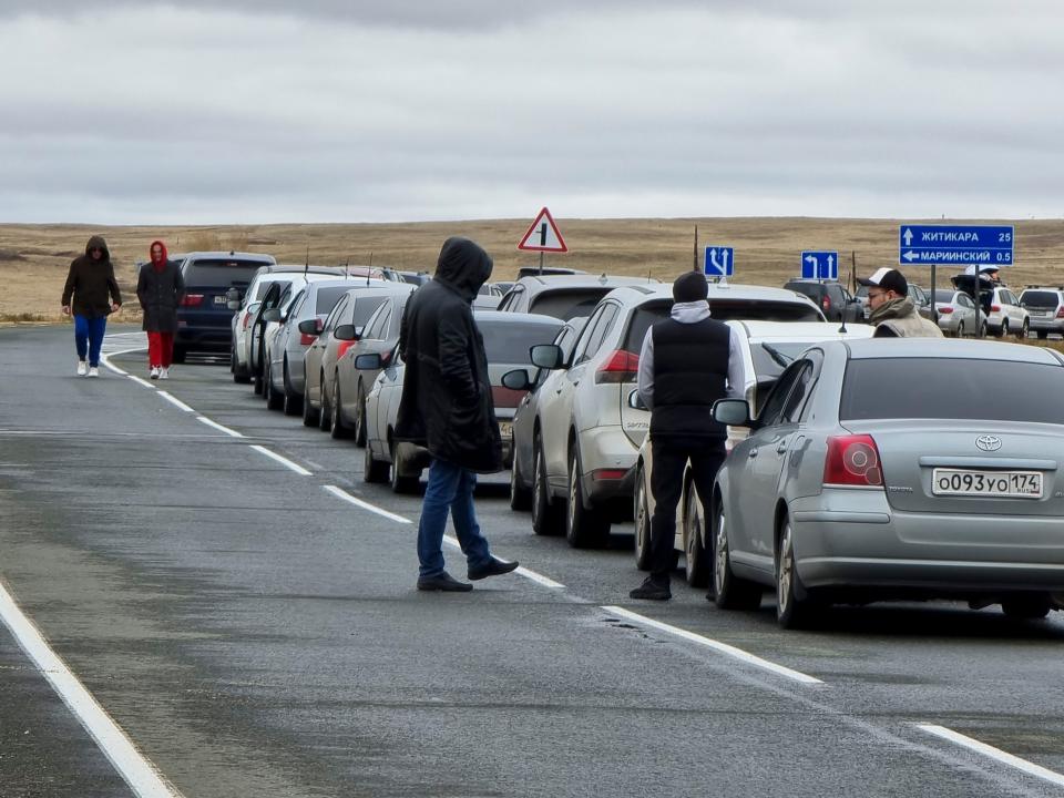 People walk next to their cars queuing to cross the border into Kazakhstan.