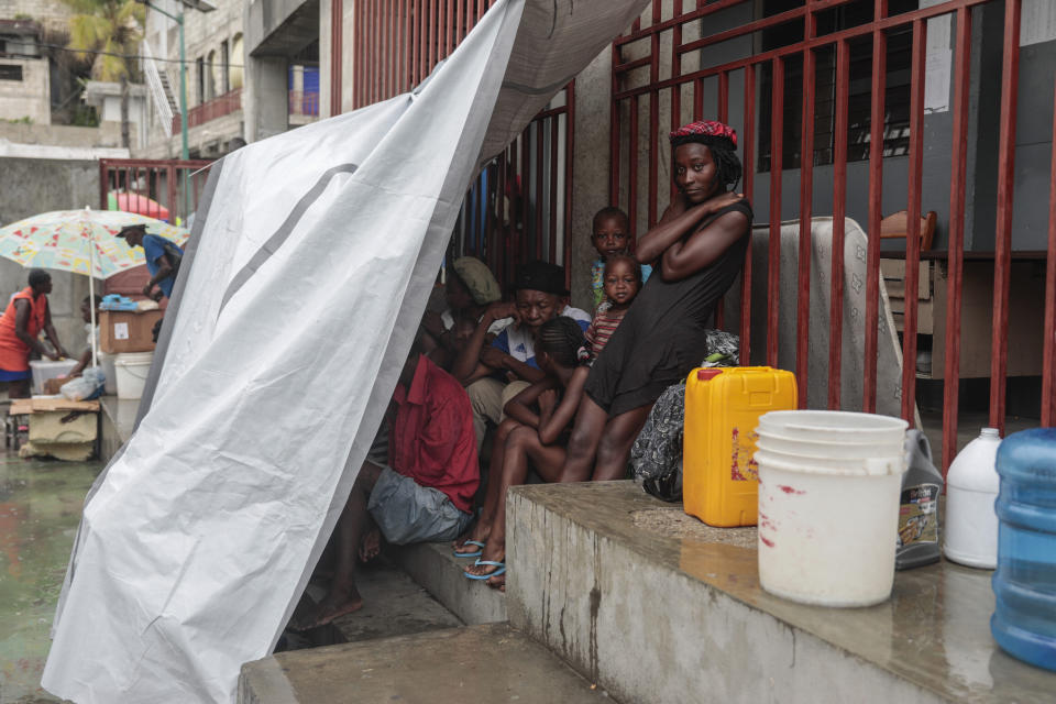 Personas desplazadas en el patio de una escuela donde se están refugiando debido a la violencia de pandillas, mientras llueve a causa de la tormenta tropical Franklin, el miércoles 23 de agosto de 2023, en Puerto Príncipe, Haití. (AP Foto/Odelyn Joseph)