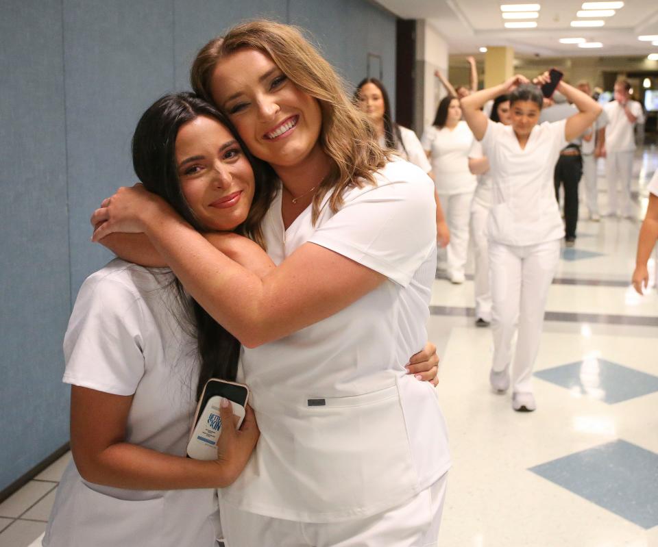 Laney Sazera and Hannah Reid share a hug as they walk down the hall to begin the nurse pinning and lamp ceremony Thursday, Aug. 3, 2023, at Shelton State.