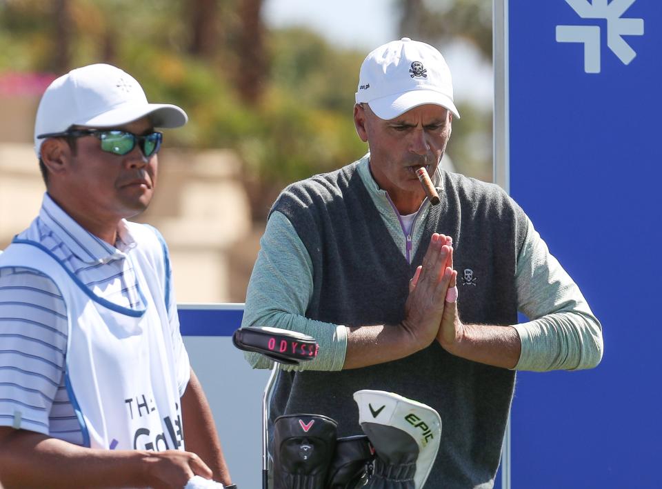 Rocco Mediate smokes a cigar while stretching out before his first tee shot of the day at the Galleri Classic at Mission Hills Country Club in Rancho Mirage, March 25, 2023.  At left is Vijay SinghÕs caddie Charlly Pak. 