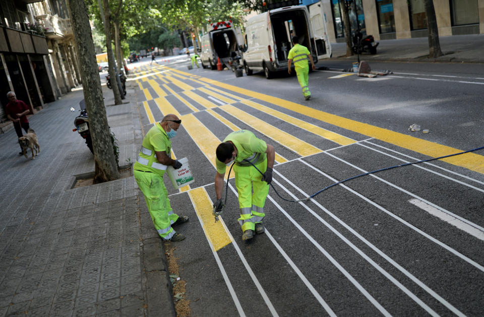 Workers paint lines on the street In Barcelona to expand a sidewalk for pedestrians.