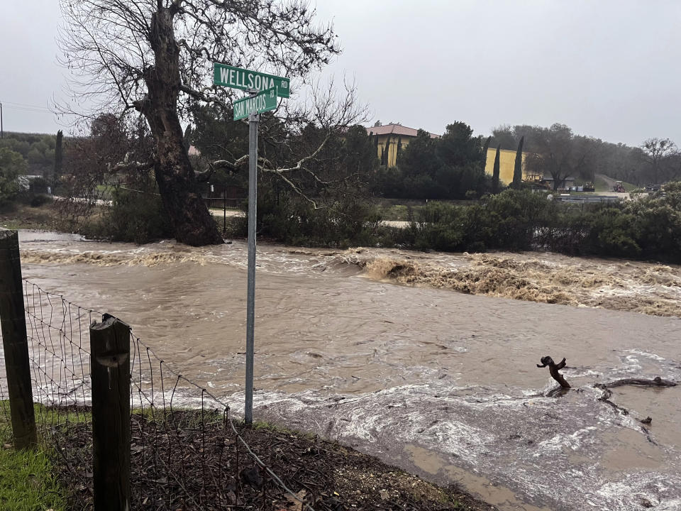 In this photo provided by Neil Collins, floodwaters continue to flow at the intersection of Wellsona Rd. and San Marcos Rd. near the San Marcos Creek in San Miguel, Calif., on Monday, Jan. 9, 2023. Search efforts for 5-year-old Kyle Doan, who was swept away Monday, Jan. 9, by rising floodwaters after his mother's truck was hit by water currents, continued for a third day, Wednesday, Jan. 11. (Neil Collins via AP)
