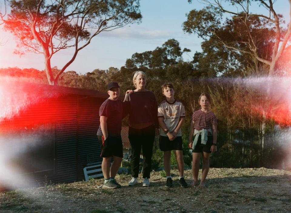 Harry with mum Margie and siblings Oscar, 13, and Romy, 9, in the backyard of their fire-damaged family home (Matthew Abbott/Save the Children)