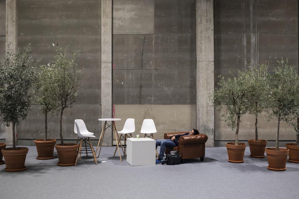 A visitor rests at the at the COP25 summit in Madrid, Sunday Dec. 15, 2019. Negotiators from almost 200 nations planned to gather for a final time at the U.N. climate meeting in Madrid early Sunday to pass declarations calling for greater ambition in cutting planet-heating greenhouse gases and in helping poor countries suffering the effects of climate change. But one of the key issues at the talks, an agreement on international carbon markets, has eluded officials even after the Chilean chair extended Friday's talks deadline to allow more time for negotiations. (AP Photo/Bernat Armangue)