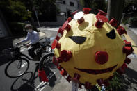 A man wearing a protective mask to help curb the spread of the coronavirus rides a bicycle past a scarecrow depicting coronavirus displayed at a street Monday, Sept. 28, 2020, in Tokyo. The Japanese capital confirmed more than 70 coronavirus cases on Monday. (AP Photo/Eugene Hoshiko)
