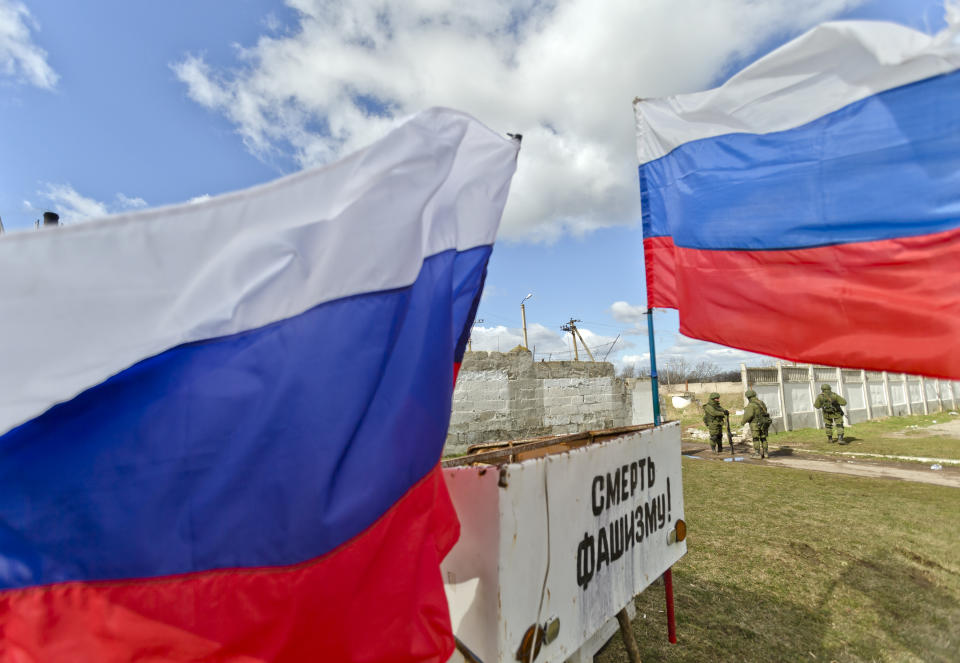 Russian flags decorate a vehicle as pro-Russian soldiers stand outside a Ukrainian military base in Perevalne, Ukraine, Monday, March 17, 2014. Crimea's parliament on Monday declared the region an independent state, after its residents voted overwhelmingly to break off from Ukraine and seek to join Russia. Writing reads: "Death to Fascism." (AP Photo/Vadim Ghirda)