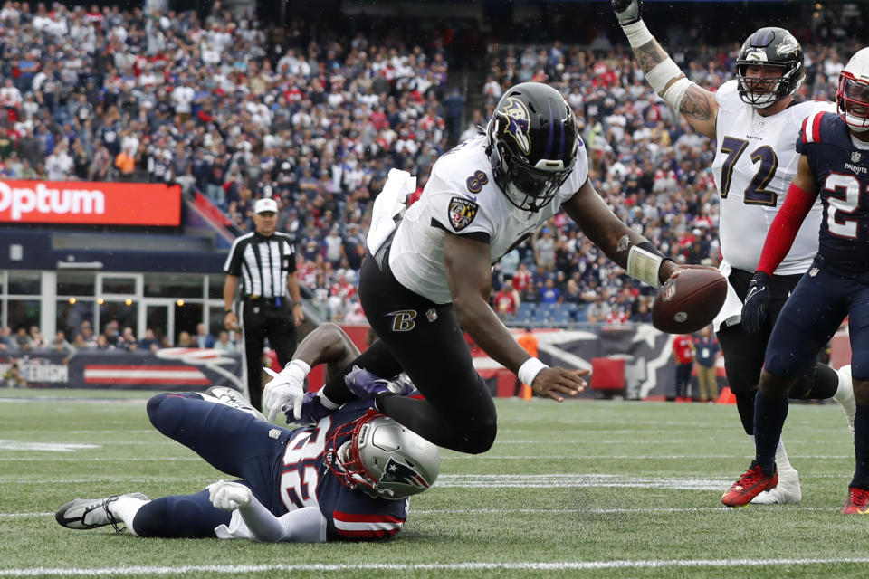Baltimore Ravens quarterback Lamar Jackson (8) scores a touchdown as New England Patriots safety Devin McCourty (32), below left, tries to defend in the second half of an NFL football game, Sunday, Sept. 25, 2022, in Foxborough, Mass. (AP Photo/Michael Dwyer)