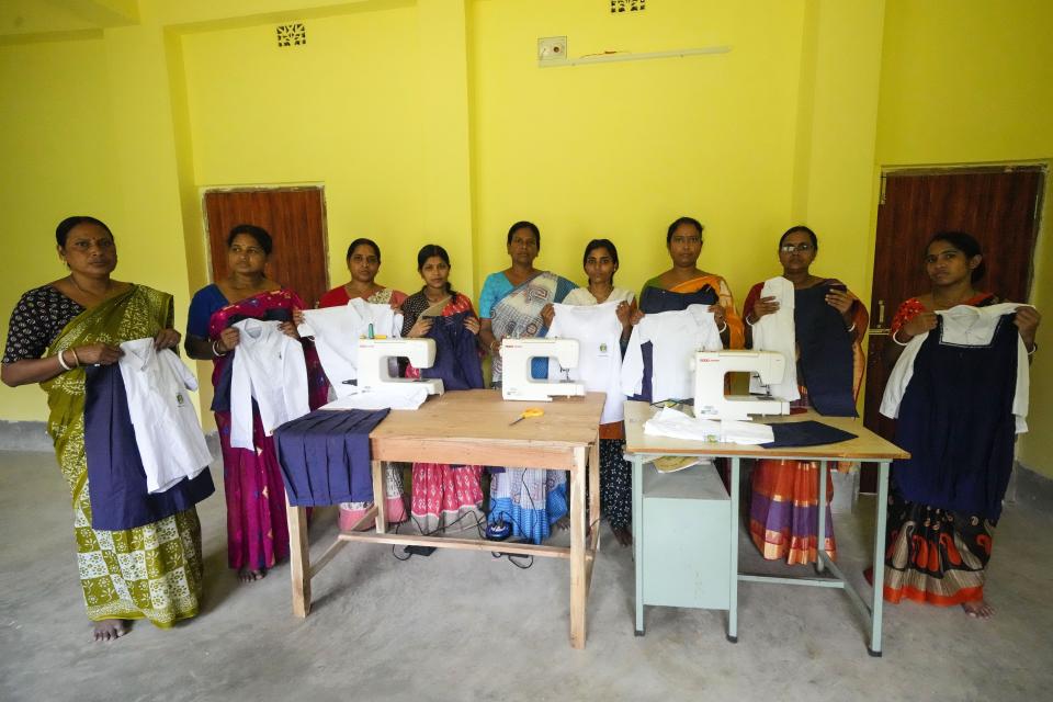 Kakali Halder, center, along with members display finished school uniforms in Mathurapur, South 24 Parganas, India, Monday, March 27, 2023. Halder and several hundred fellow seamstresses at Mathurapur Sanghati Swayamber Sangha, a group that make clothing items and share the proceeds between them, have worked with the stress of trying to get orders out when they can't rely on the electricity. (AP Photo/Bikas Das)