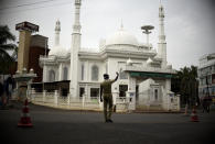 An Indian policeman directs traffic outside a Mosque closed for devotees due to the pandemic lockdown during Ramadan in Kochi, Kerala state, India, Friday, May 22, 2020. Muslims worldwide will celebrate one of their biggest holidays under the long shadow of the coronavirus, with millions confined to their homes and others gripped by economic concerns during what is usually a festive time of shopping and celebration. (AP Photo/R S Iyer)