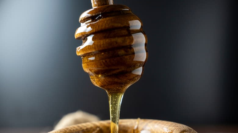 Honey dripping from a honey dipper into a bowl