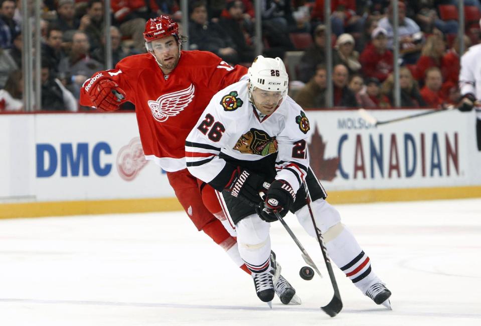 Chicago Blackhawks center Michal Handzus (26), of Czech Republic, tries to control the puck as Detroit Red Wings right wing Patrick Eaves defends in the first period of an NHL hockey game Wednesday, Jan. 22, 2014, in Detroit. (AP Photo/Paul Sancya)