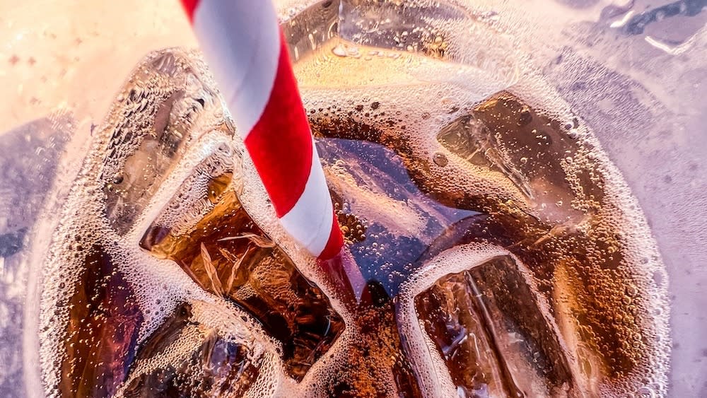  Close up on a striped red and white straw inside a fizzy glass of diet soda. 