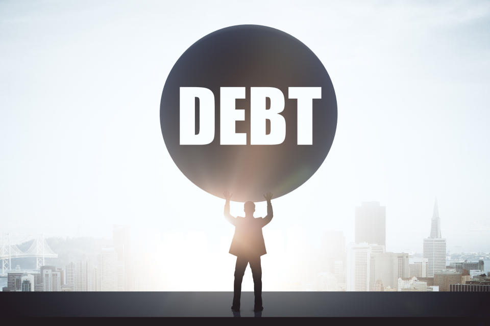 Man holding up large ball with the word debt on it