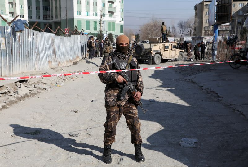 An Afghan security officer stands guard at the site of a bomb blast in Kabul