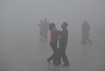 FILE PHOTO: People wearing masks dance amid heavy smog during a polluted day at a square in Fuyang, Anhui province, China January 3, 2017. China Daily via REUTERS/File Photo