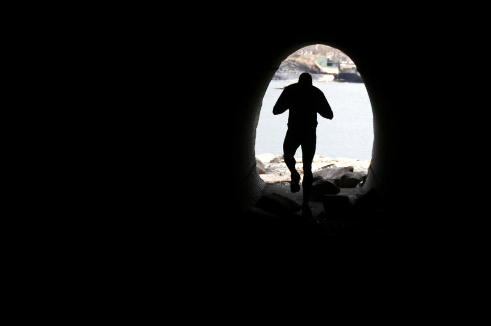 FILE - In this Wednesday, March 27, 2013 file photo, a runner exits a debris-filled tunnel that is part of the Cliff Walk, in Newport, R.I. Large portions of the Cliff Walk damaged by Superstorm Sandy have yet to be repaired as the summer tourist season approaches. (AP Photo/Steven Senne, File)