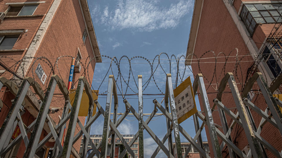 A barbed-wire fence stands at sealed off residential compound near the Yuquandong market, in Haidian district, Beijing, China. Source: AAP
