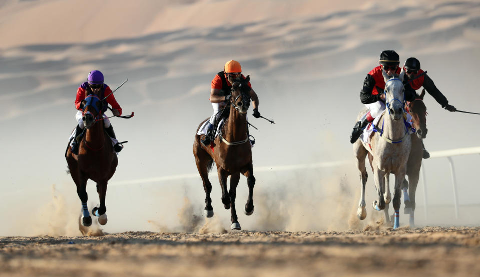 <p>Jockeys on purebred Arab horses race during the 2018 Moreeb Dune Festival on Jan. 1 in the Liwa desert, some 250 kilometers west of Abu Dhabi. (Photo: Karim Sahib/AFP/Getty Images) </p>