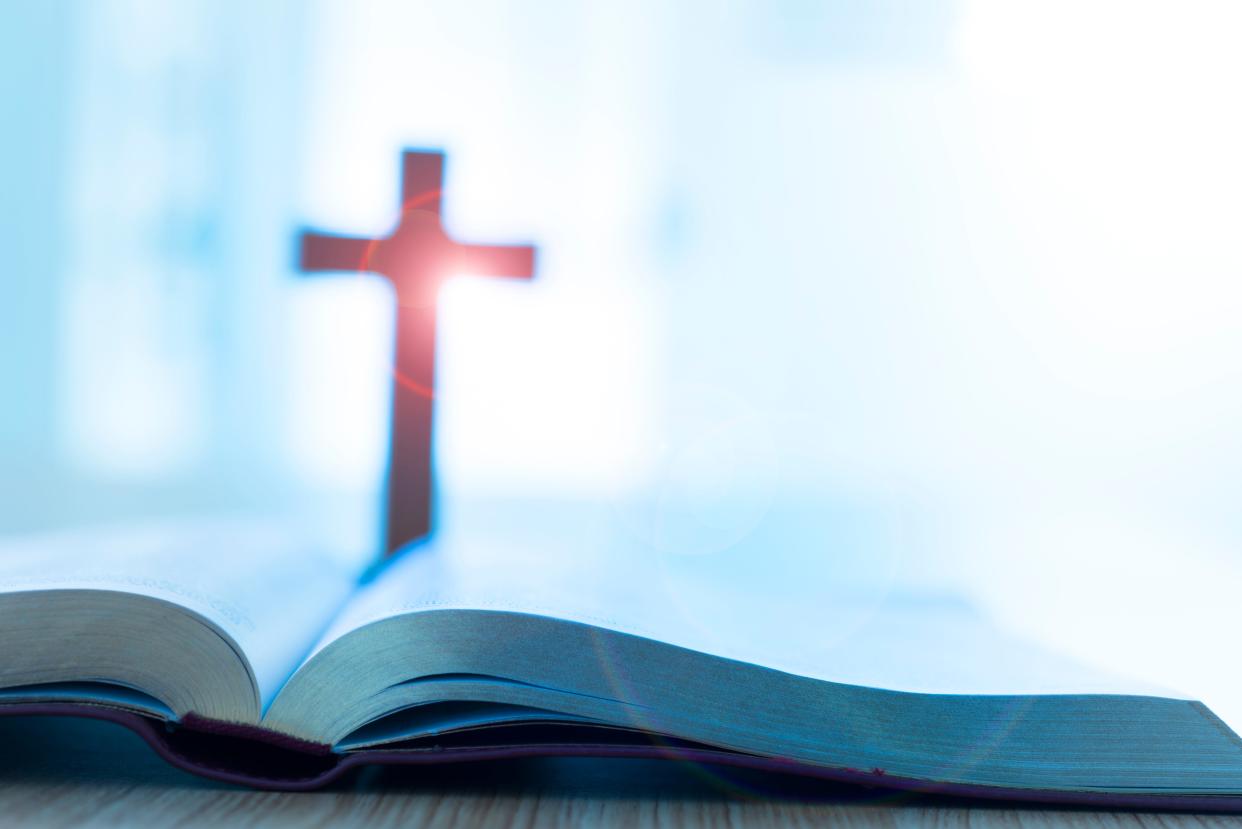 Bible and cross on desk.