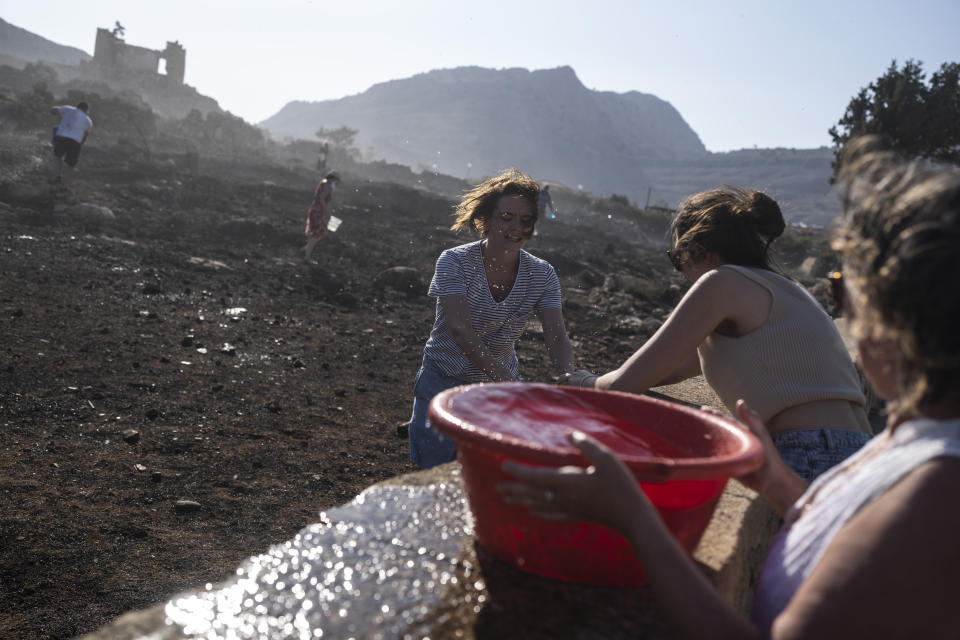 FILE - German tourists together with local residents try to extinguish a fire, near the seaside resort of Lindos, on the Aegean Sea island of Rhodes, southeastern Greece, on July 24, 2023. Greece’s resort island of Rhodes is nursing its wounds after 11 days of devastating wildfires. (AP Photo/Petros Giannakouris, File)