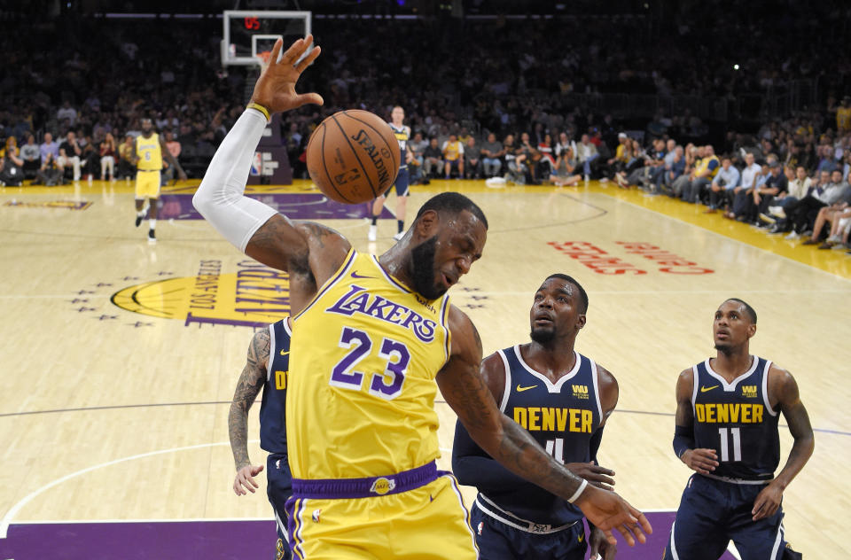 FILE - In this Tuesday, Oct. 2, 2018, file photo, Los Angeles Lakers forward LeBron James, left, dunks as Denver Nuggets forward Paul Millsap, center, and guard Monte Morris watch during the first half of an NBA basketball game in Los Angeles. James says he didn’t choose the Lakers as his free-agent destination because of his burgeoning career as a Hollywood producer and performer. He remains focused on basketball, and he wants to create a winning team to end the Lakers’ franchise-record five years without a playoff berth. (AP Photo/Mark J. Terrill, File)