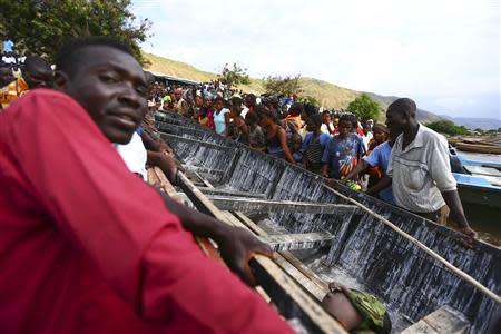 Residents surround a canoe containing retrieved bodies after a boat carrying mostly Congolese refugees capsized at the shores of Lake Albert during rescue operations by the Uganda Marine Unit in Ntoroko southwest of Uganda's capital Kampala, March 23, 2014. REUTERS/Edward Echwalu