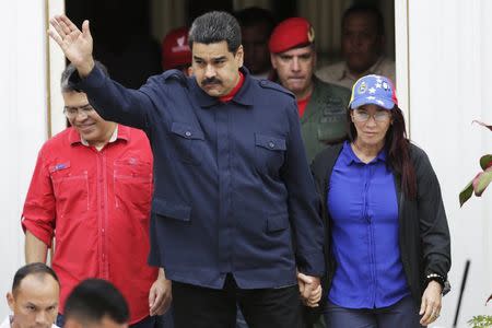 Venezuela's President Nicolas Maduro (C) greets supporters as he arrives to a rally against the opposition's law granting titles of property to beneficiaries of Mission Housing, a low-income social housing project, next to his wife and deputy of Venezuela's United Socialist Party (PSUV) Cilia Flores (R), in Caracas April 14, 2016. REUTERS/Marco Bello