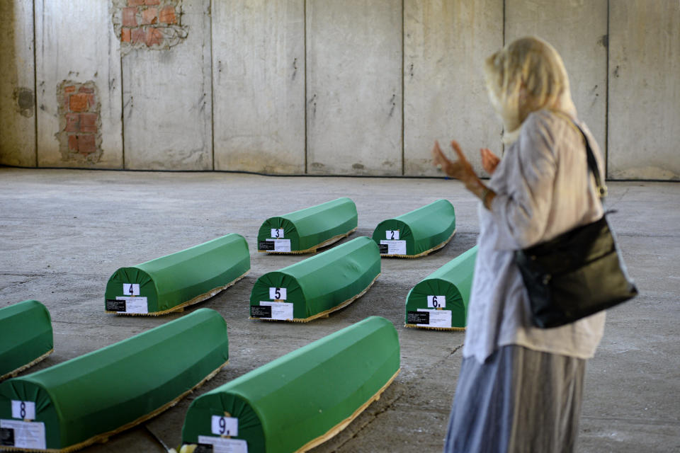 A woman prays next to victims' coffins inside the former UN base in Potocari, near Srebrenica, Bosnia, Friday, July 10, 2020. Nine newly found and identified men and boys will be laid to rest when Bosnians commemorate on Saturday 25 years since more than 8,000 Bosnian Muslims perished in 10 days of slaughter, after Srebrenica was overrun by Bosnian Serb forces during the closing months of the country's 1992-95 fratricidal war, in Europe's worst post-WWII massacre. (AP Photo/Kemal Softic)