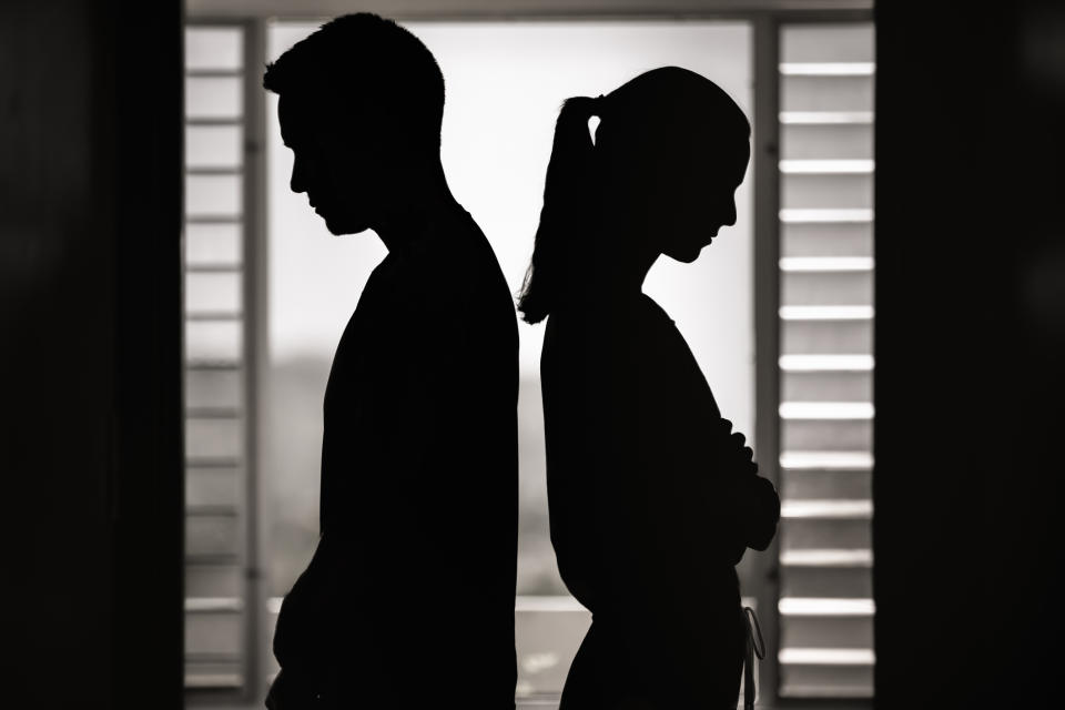 Silhouettes of a man and woman facing away from each other, suggesting emotional distance or a disagreement