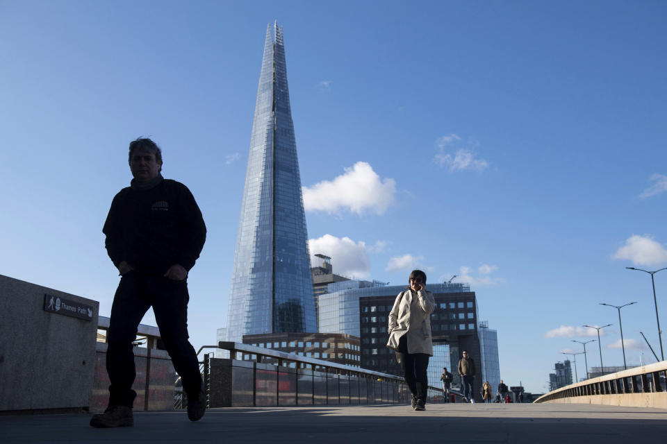 People cross London Bridge backdropped by the Shard skyscraper as workers return to offices following the Easter holiday, in London, Tuesday April 6, 2021.  Virus lockdown restrictions are eased in England to allow far greater freedom outdoors. (Dominic Lipinski/PA via AP)