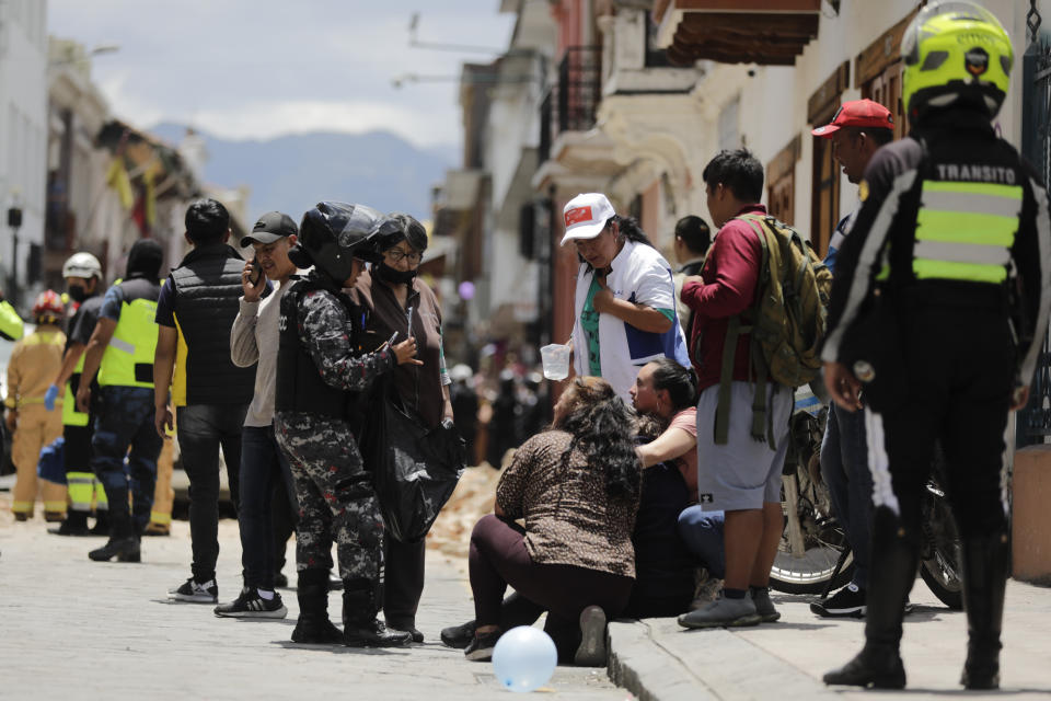 La policía habla con las personas junto al sitio donde un automóvil fue aplastado por los escombros después de un fuerte sismo que sacudió Cuenca, Ecuador, el sábado 18 de marzo de 2023. El Servicio Geológico de EEUU informó que el terremoto con una magnitud de 6,7 se registró a unas 50 millas al sur de Guayaquil. (Foto AP/Xavier Caivinagua)