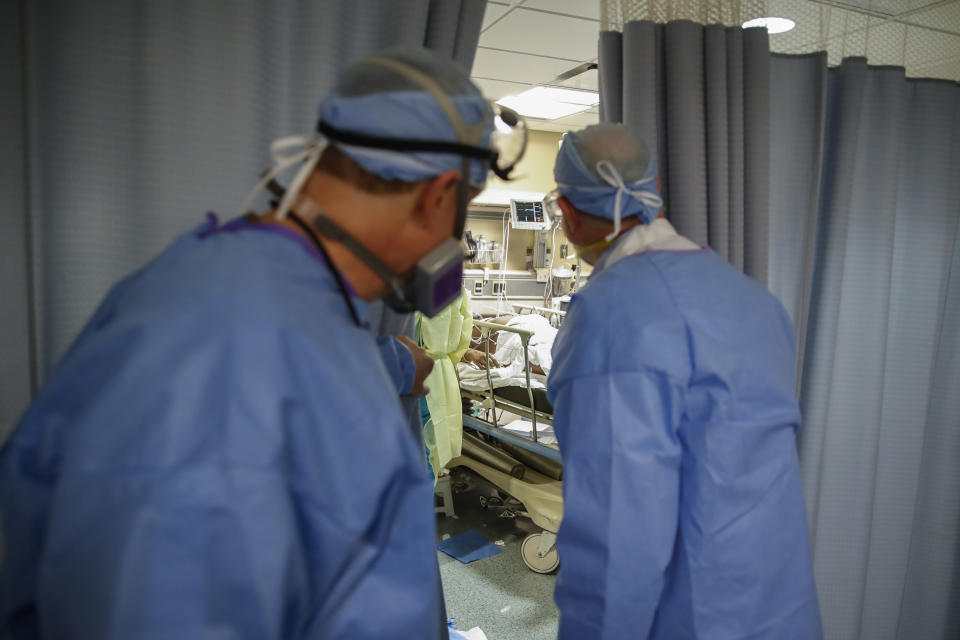 Dr. Anthony Leno, Director of Emergency Medicine St. Joseph's Hospital, left, and Dr. James Neuendorf, Director of Medicine, right, look into an exam room where a patient with COVID-19 who went into cardiac arrest was revived, Monday, April 20, 2020, in Yonkers, N.Y. (AP Photo/John Minchillo)