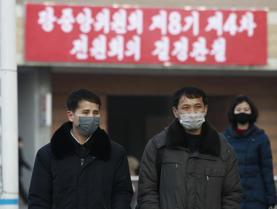 People wearing face masks walk on the street near the Pyongyang railway station in Pyongyang, North Korea, Thursday, Jan. 27, 2022. The red banner says, "Implementation of decisions of the Forth Plenary Meeting of the Eighth Central Committee of Workers' Party of Korea." (AP Photo/Cha Song Ho)