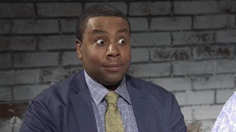 Kenan Thompson, wearing a suit and tie, makes a surprised facial expression during a comedy skit