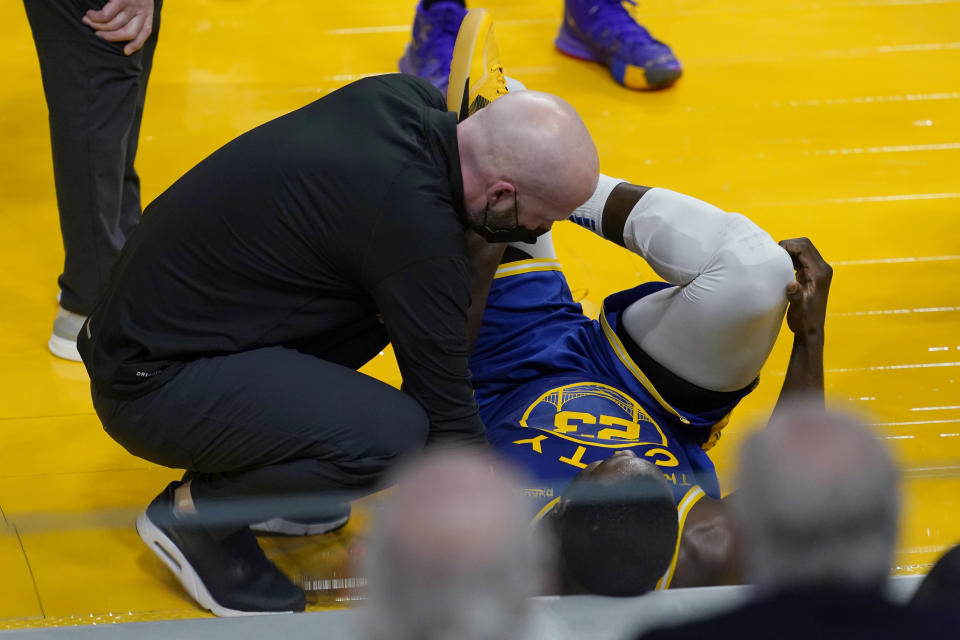 Golden State Warriors forward Draymond Green, right, receives medical attention during the first half of the team's NBA basketball game against the Brooklyn Nets in San Francisco, Saturday, Feb. 13, 2021. (AP Photo/Jeff Chiu)