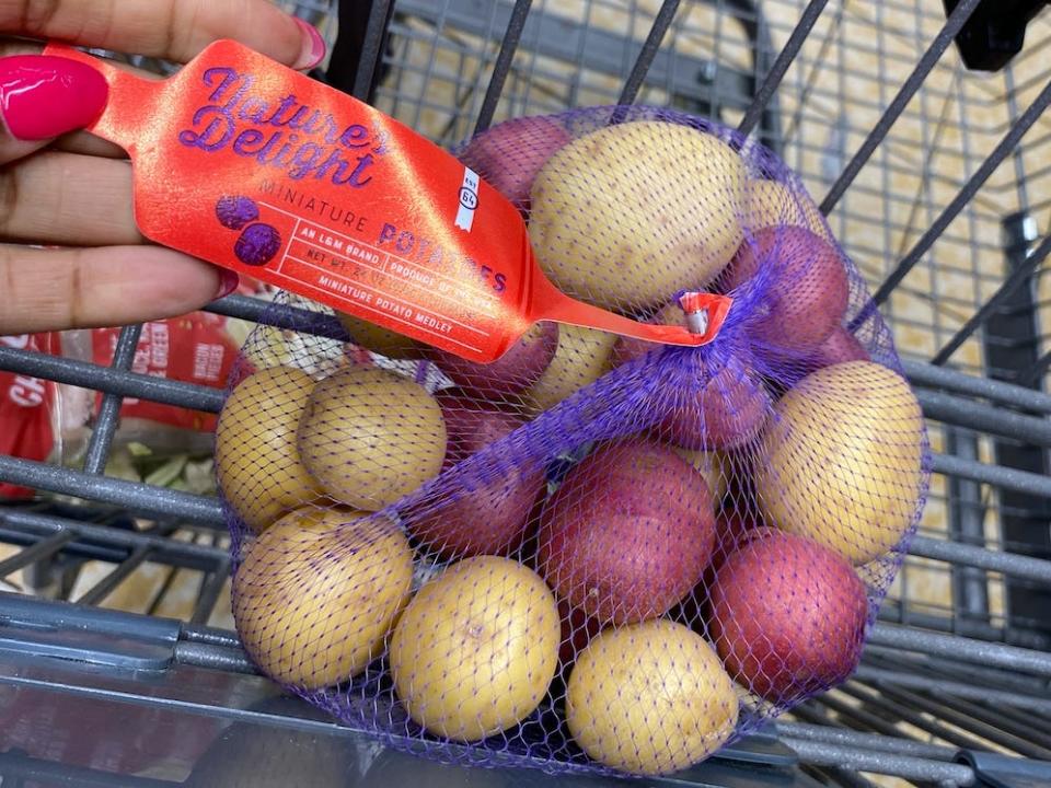 hand grabbing a bag of mini potatoes form a cart. ataldi