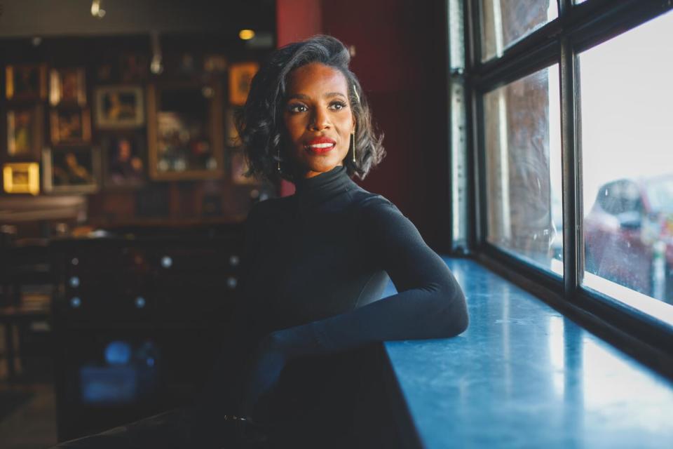 Woman dressed in all black sitting at a bar and looking out the window