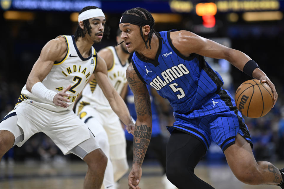 Orlando Magic forward Paolo Banchero (5) drives to the basket as Indiana Pacers guard Andrew Nembhard (2) defends during the first half of an NBA basketball game, Sunday, March 10, 2024, in Orlando, Fla. (AP Photo/Phelan M. Ebenhack)
