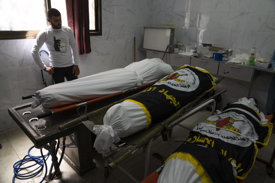 A Palestinian man looks at the bodies of Mahmoud Abdeljawwad, left, and Mohammed Ghali, center, who were killed in an Israeli airstrike alongside Islamic Jihad commander Ali Ghali, right, prior to their funeral in Khan Younis, southern Gaza Strip, May 11, 2023. / Credit: Fatima Shbair/AP
