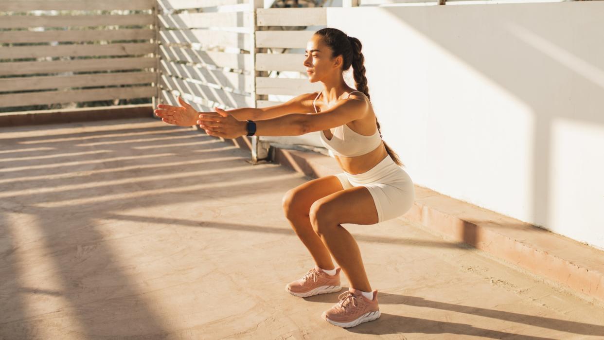  A photo of a woman doing a bodyweight squat. 